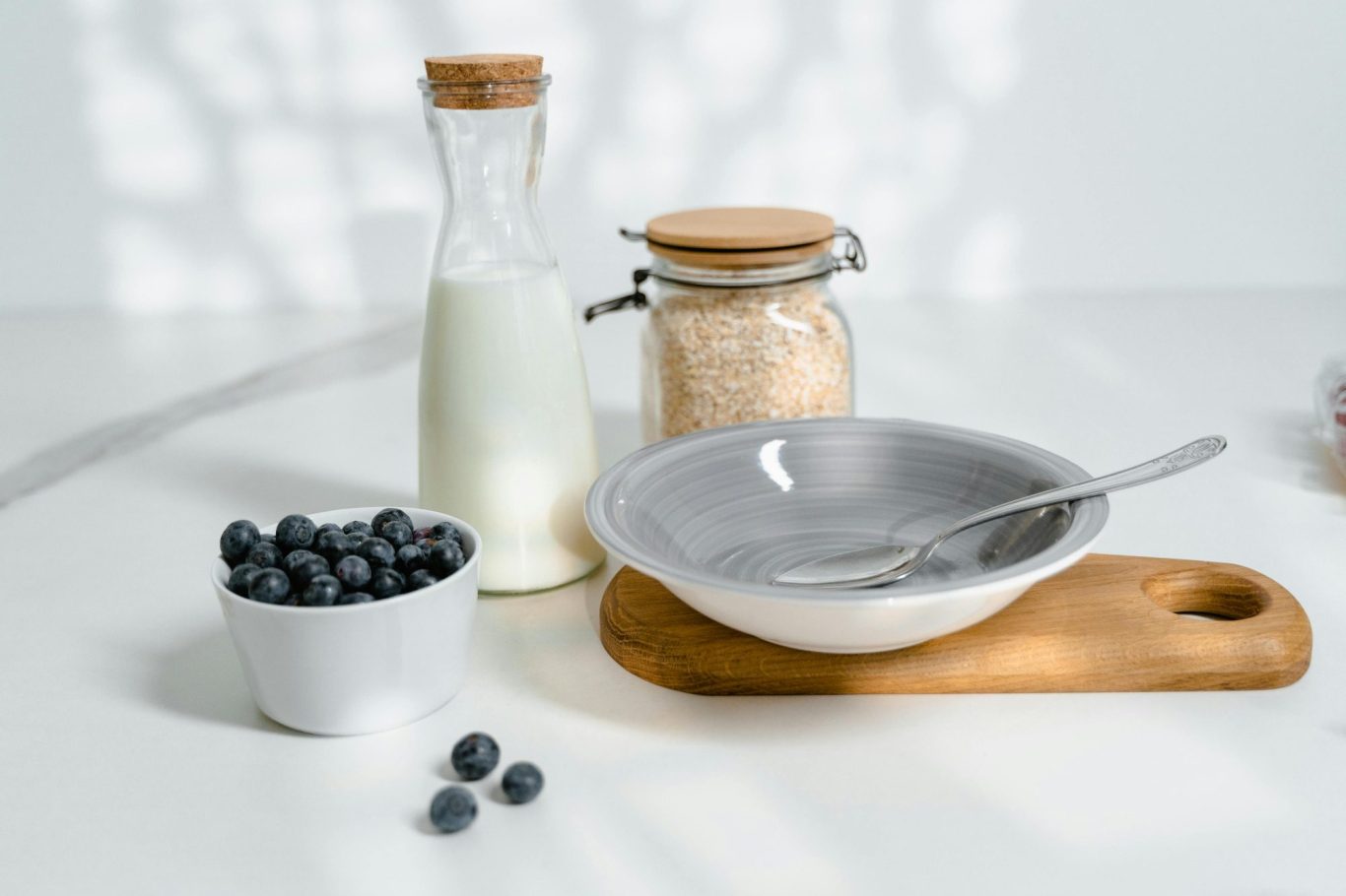 Milch in Glasflasche neben Blaubeeren, Haferflocken und Schale